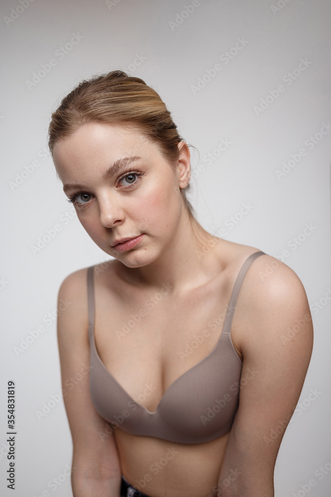 pretty caucasian girl wearing beige bra with naked shoulders looking at camera. beauty portrait, close up. beautiful woman with perfect clean skin on white studio background. plus size model tests pretty caucasian girl wearing beige bra with naked shoulders looking at camera. beauty portrait, close up. beautiful woman with perfect clean skin on white studio background. plus size model tests