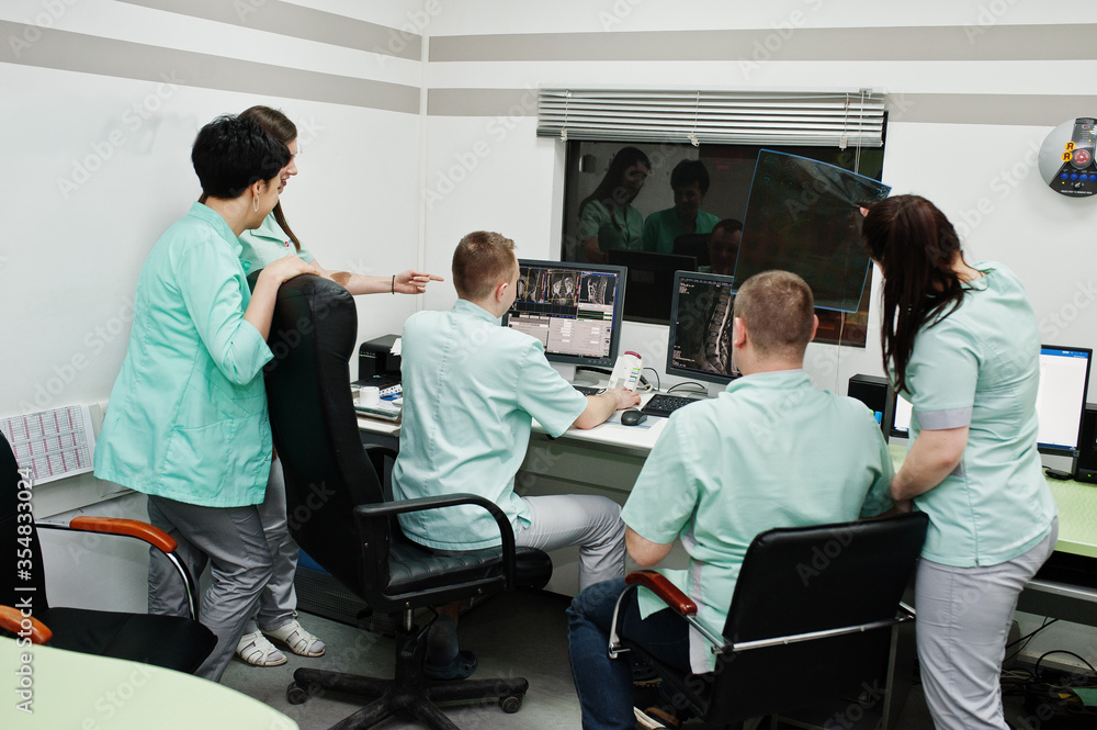 Medical theme.Observation room with a computer tomograph. The group of doctors meeting in the mri office at diagnostic center in hospital. Hold x-ray radiographic image. Medical theme.Observation room with a computer tomograph. The group of doctors meeting in the mri office at diagnostic center in hospital. Hold x-ray radiographic image.