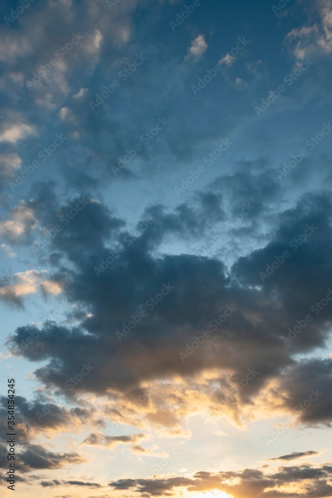 sun sets behind the clouds in the blue evening sky as a natural background