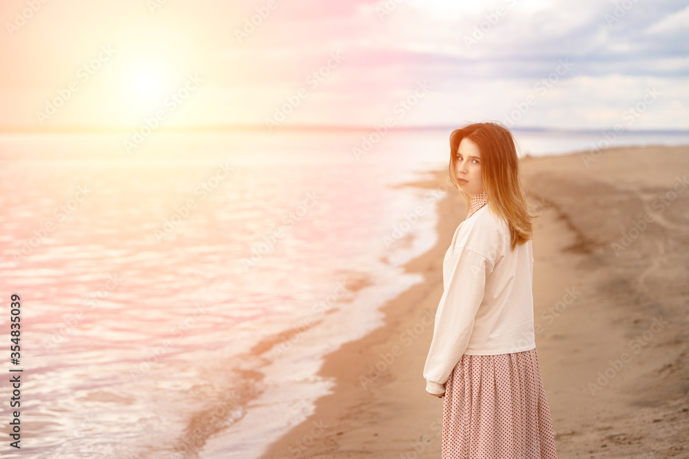 A young beautiful girl walks along the shore and looks back. A young beautiful girl walks along the shore and looks back.