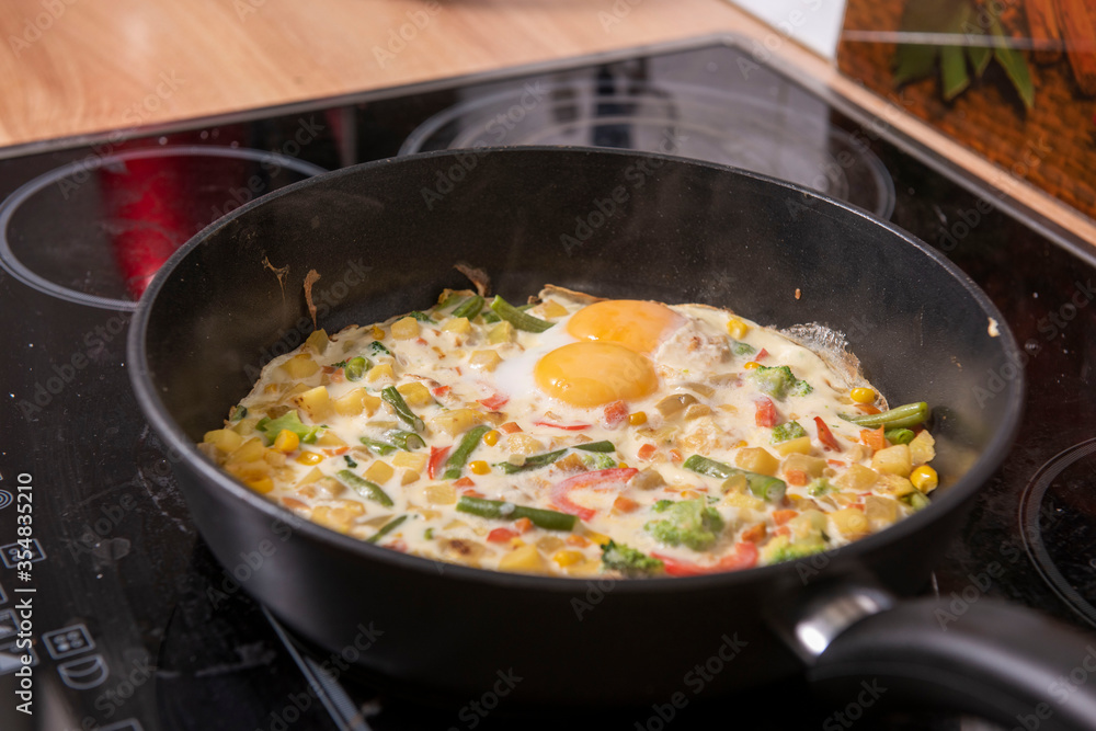 In a black pan, appetizer omelet fried eggs with fresh vegetables. In a black pan, appetizer omelet fried eggs with fresh vegetables.