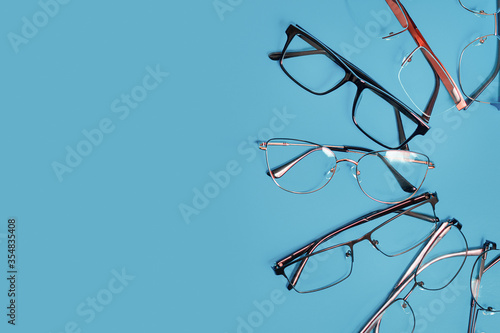 Set of corrective medical spectacles of various shapes. Blue background with copy space
