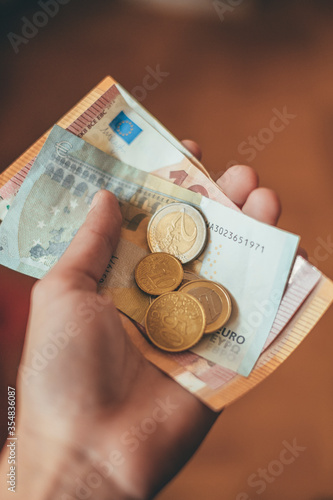 A person is holding some notes and coins in his hand. Concept finance, pay, Euro and money transactions.