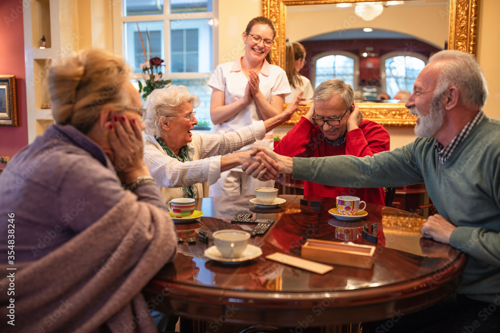 Older folks shaking hands over a game result Older folks shaking hands over a game result