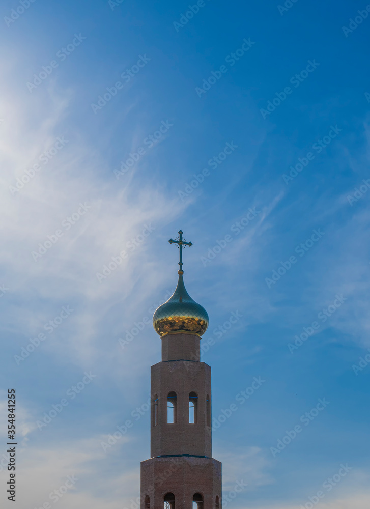 The dome of the Christian church with a cross on a background of blue sky. New building.