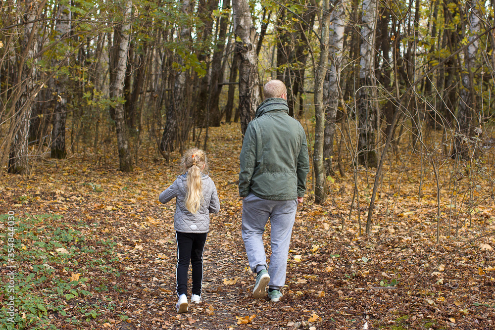 Fototapeta premium Man and girl walking in the autumn forest