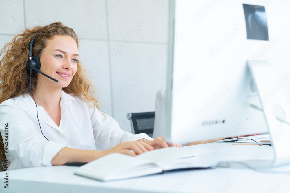 Young friendly operator woman agent with headsets working in a call center, smile and hand touch at headphone concept for service mind in the call center Young friendly operator woman agent with headsets working in a call center, smile and hand touch at headphone concept for service mind in the call center