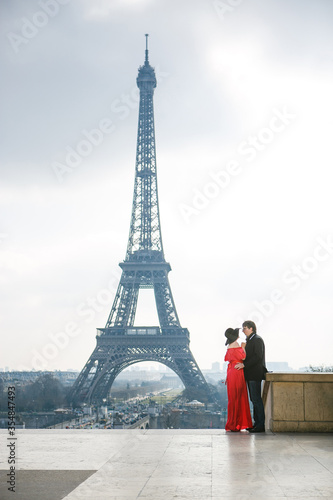 man and woman in red dress and hat on Eiffel tower in Paris. symbol of France. © andrey