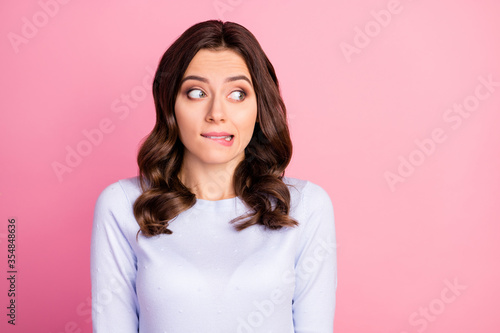 Photo of attractive lady wavy hairdo biting lips look shy side empty space made wrong bad thing uncomfortable situation wear casual white pullover isolated pink color background