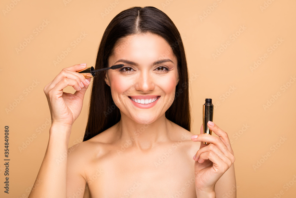 Closeup photo of attractive latin naked lady model holding eyelash bottle applying one eye making night makeup preparing date isolated beige pastel color background Closeup photo of attractive latin naked lady model holding eyelash bottle applying one eye making night makeup preparing date isolated beige pastel color background
