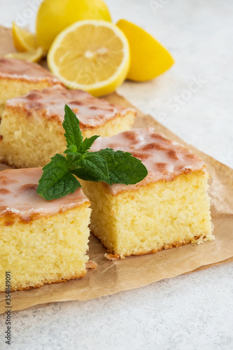 Lemon cake on baking paper. Pieces of cake with zest, decorated sugar icing and mint. Close up
