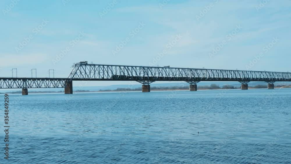 freight train rides over the bridge.Railway bridge over the river. Sunny spring day. freight train rides over the bridge.Railway bridge over the river. Sunny spring day.
