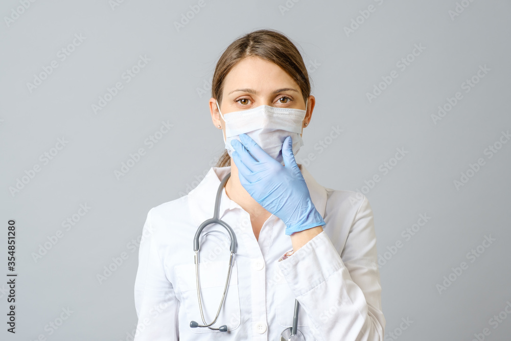 Portrait of doctor putting sterile mask isolated on gray Portrait of doctor putting sterile mask isolated on gray