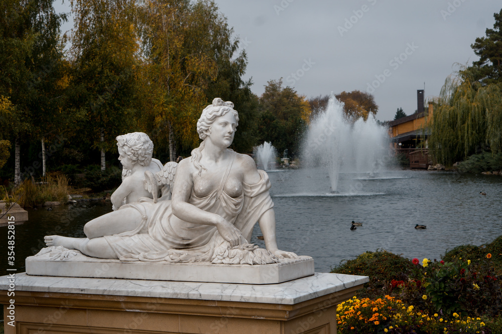 white marble statue against the backdrop of an autumn park