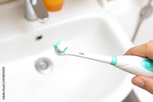 A blue and white toothbrush with paste in hand