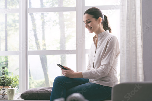Happy woman chatting with her smartphone at home Free Download Happy woman chatting with her smartphone at home - GFXLoad