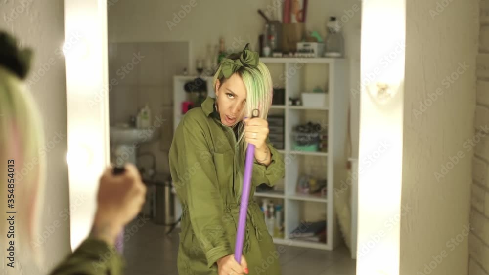 Beautiful Happy Girl Sings And Dances In Front Of A Mirror with a mop Beautiful Happy Girl Sings And Dances In Front Of A Mirror with a mop