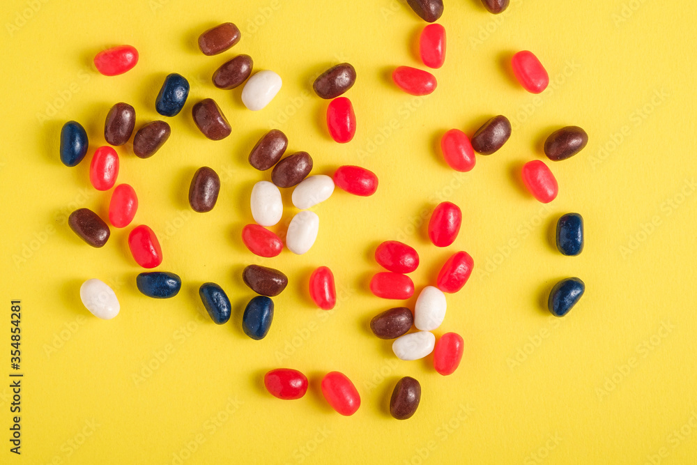 Juicy sweet fruit colorful jelly beans on bright yellow background, top view Juicy sweet fruit colorful jelly beans on bright yellow background, top view