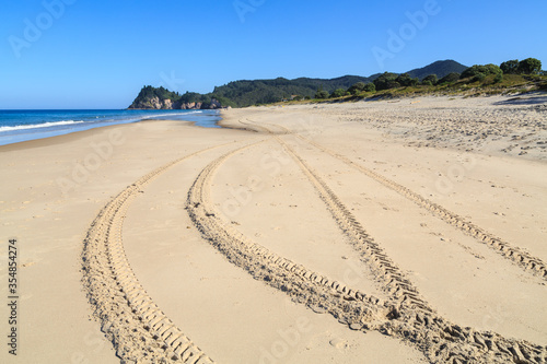 Crisscrossing tire tracks on a wide sandy beach. Whiritoa, New Zealand photo