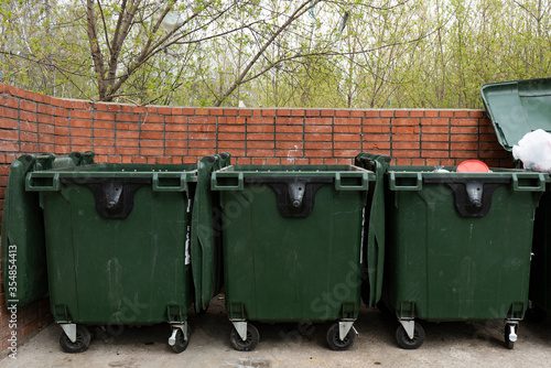 Three green trash bins in a dedicated area. © Vectorina