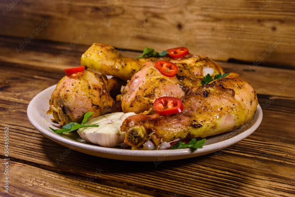 Baked chicken legs with parsley, garlic and sliced red hot pepper in a plate Baked chicken legs with parsley, garlic and sliced red hot pepper in a plate