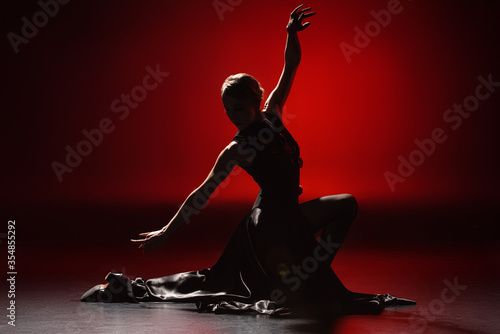 silhouette of elegant woman dancing flamenco on red