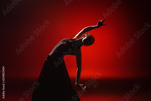 silhouette of young and attractive woman dancing flamenco on red photo