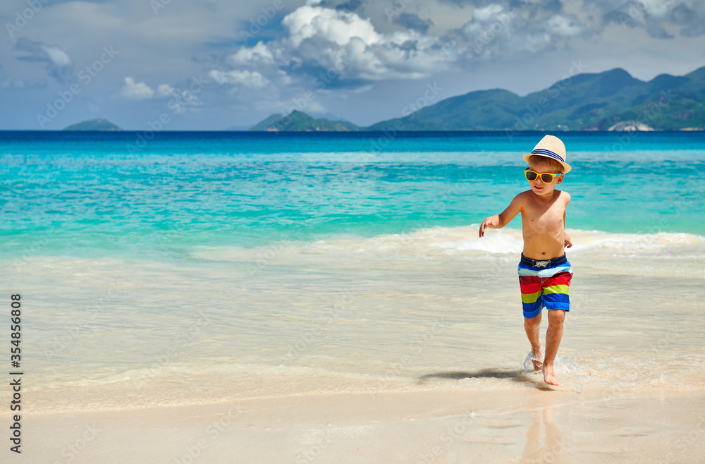 Three year old toddler boy walking on beach