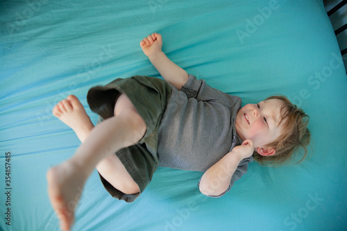 Little boy who has just woken from a sleep playing on his bed