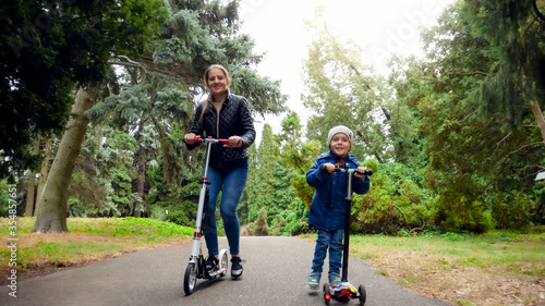 Happy smiling family riding on scooters at autumn park