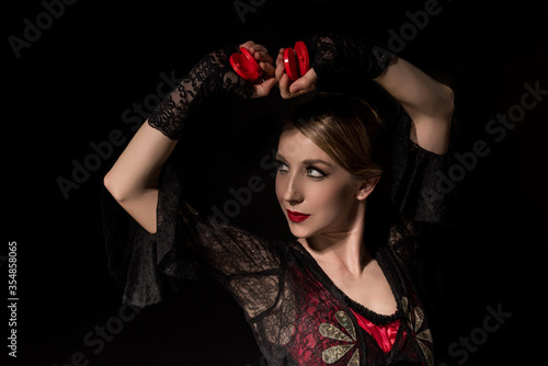 attractive dancer holding castanets while dancing flamenco isolated on black