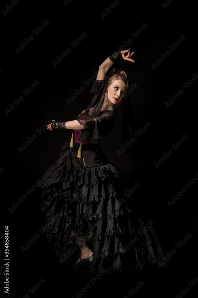 beautiful dancer looking away while dancing flamenco and gesturing isolated on black
