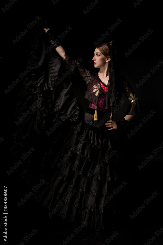 beautiful flamenco dancer in dress standing with hand on hip isolated on black beautiful flamenco dancer in dress standing with hand on hip isolated on black