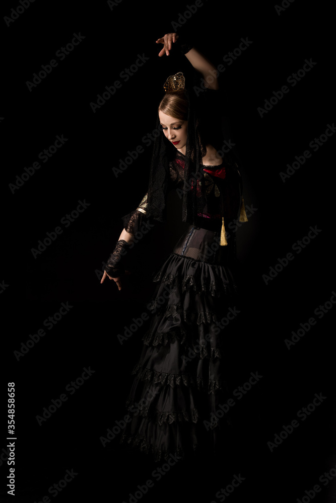 pretty dancer in dress gesturing while dancing flamenco isolated on black