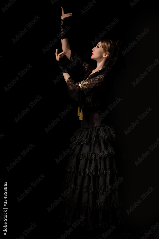 side view of pretty flamenco dancer dancing isolated on black