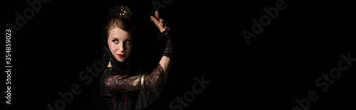 panoramic crop of pretty young dancer dancing flamenco isolated on black