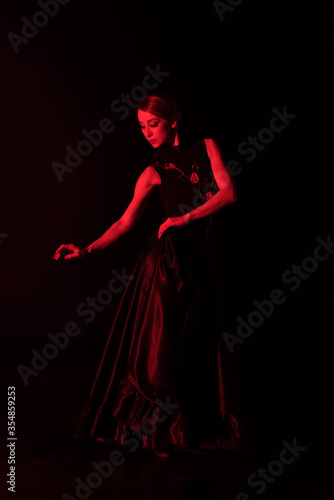red lighting on pretty young woman dancing flamenco isolated on black