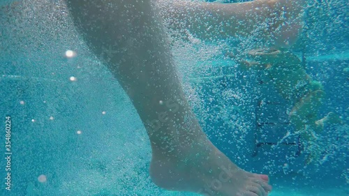 Legs Moving Underwater In Bubbles In Swimming Pool