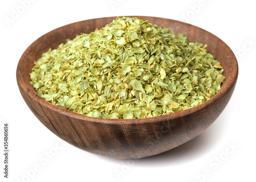 dried oregano flakes in the wooden bowl, isolated on white background