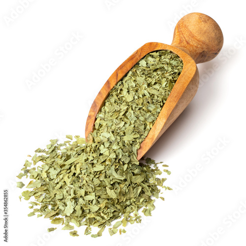 dried parsley flakes in the wooden scoop, isolated on white background