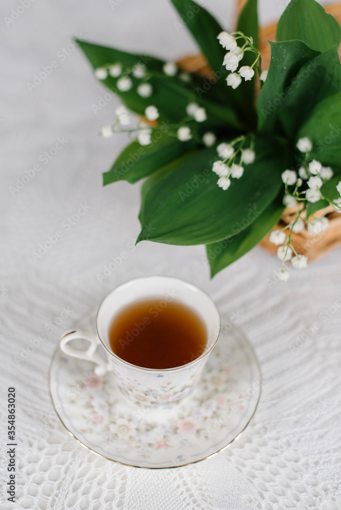 lilies of the valley in the basket and a cup of tea lilies of the valley in the basket and a cup of tea
