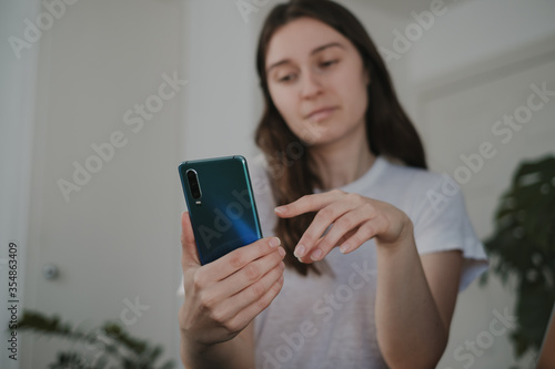 young freelancer woman texting on mobile phone working from home