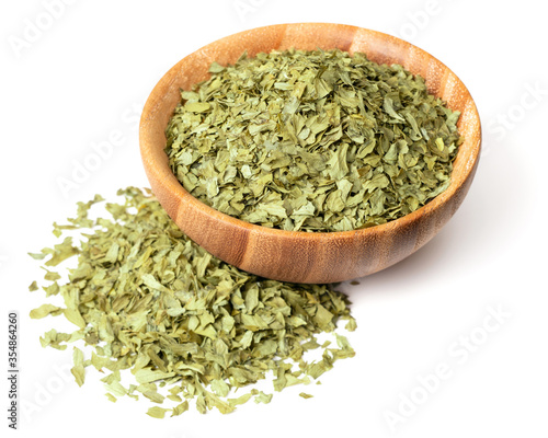 dried parsley flakes in the wooden bowl, with fresh parsley leaves, isolated on white background
