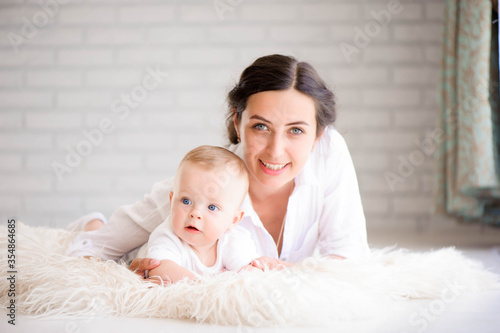 Mother and child in a white room. Mom and baby boy in diaper pla