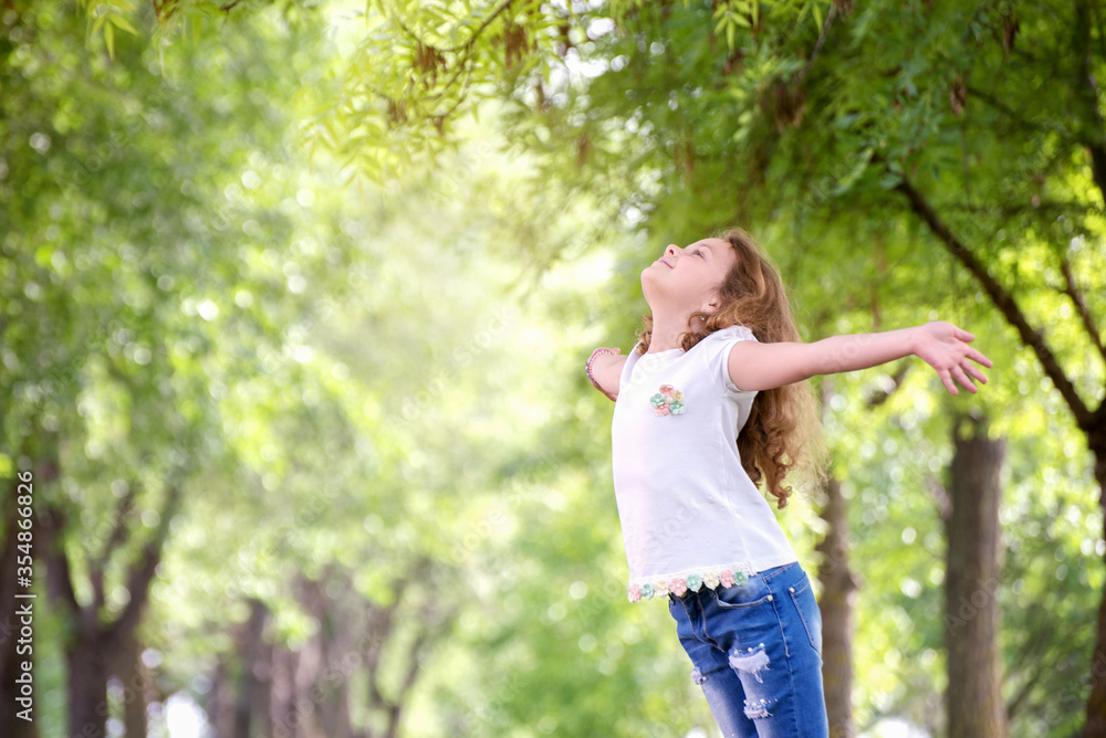 Happy girl with outstretched arms looks at the sun Happy girl with outstretched arms looks at the sun