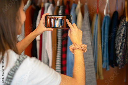 Woman taking a photo with her mobile of the wardrobe. Photograph the closet. Concept of selling clothes online.