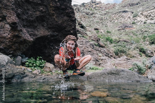 young hiker woman drinking stream water in mountain
