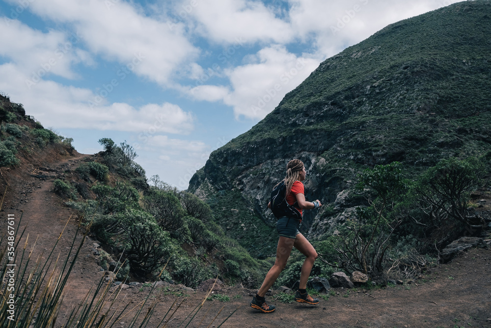 Fototapeta premium Young fitness woman trail runner running at mountain top