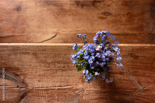 Forget-me-nots in a vase on a wooden background.