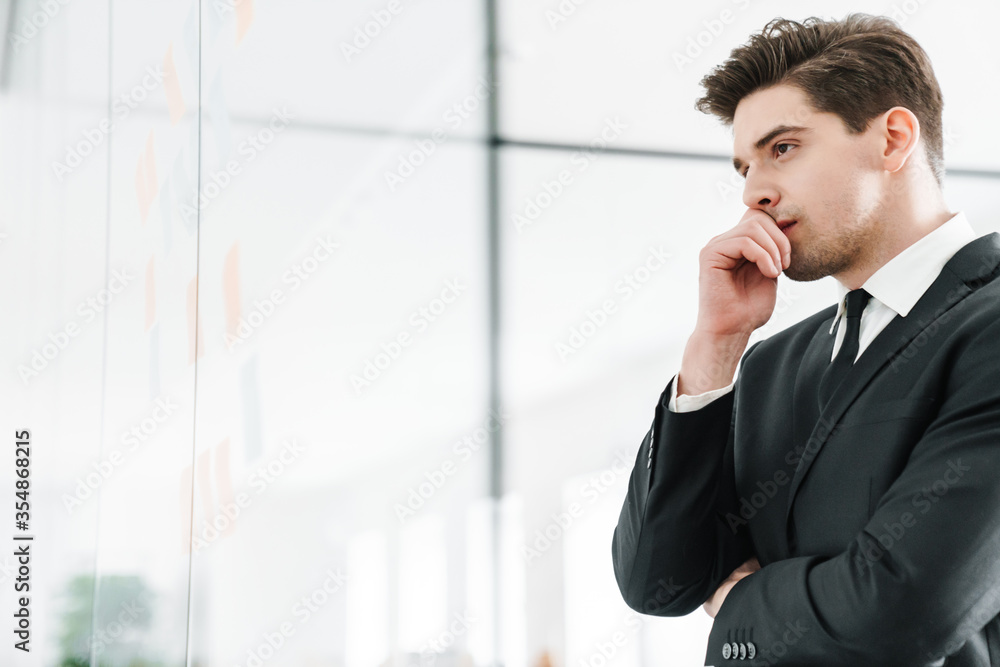Image of thinking young businessman using stickers while working Image of thinking young businessman using stickers while working